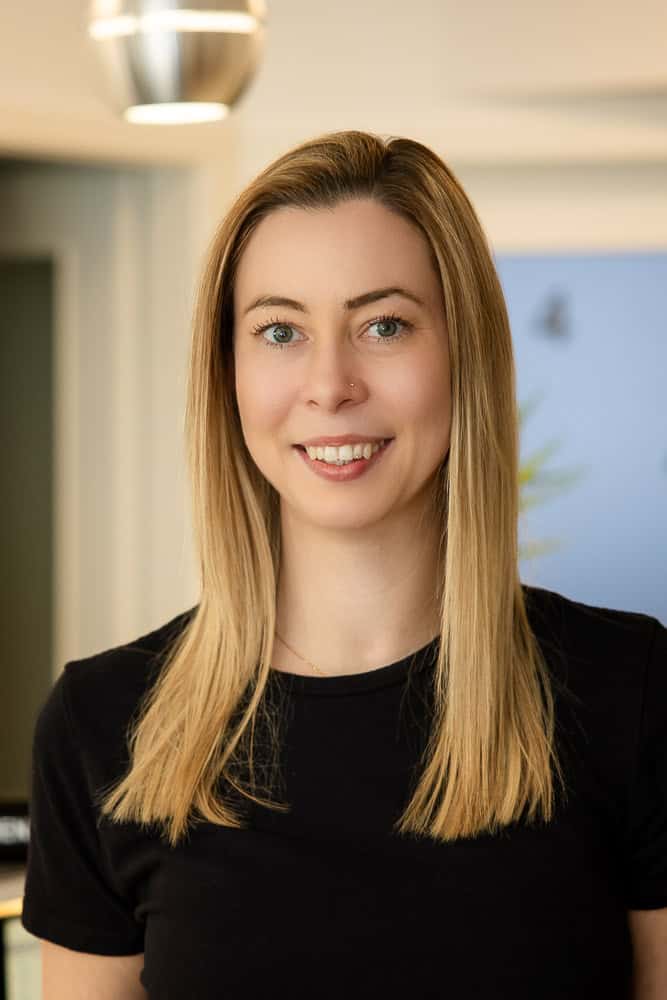 Eine junge Frau lächelt freundlich in einer Physiotherapie-Praxis.