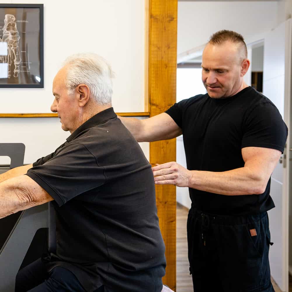 Physiotherapeut bei Behandlung eines älteren Patienten in Penzberg.