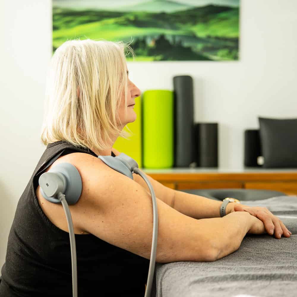 Frau bei Physiotherapie mit Elektrotherapiegerät in Penzberg.