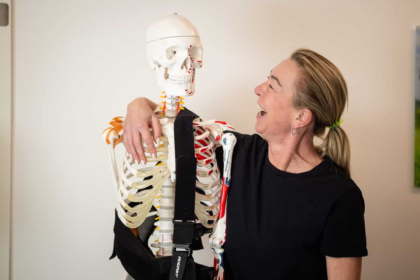 Frau erklärt einem Skelettmodell die Anatomie im Physiotherapiezentrum.