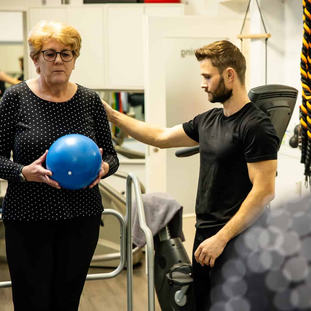 Physiotherapeutin mit älterer Patientin bei Übungen im Therapiezentrum.