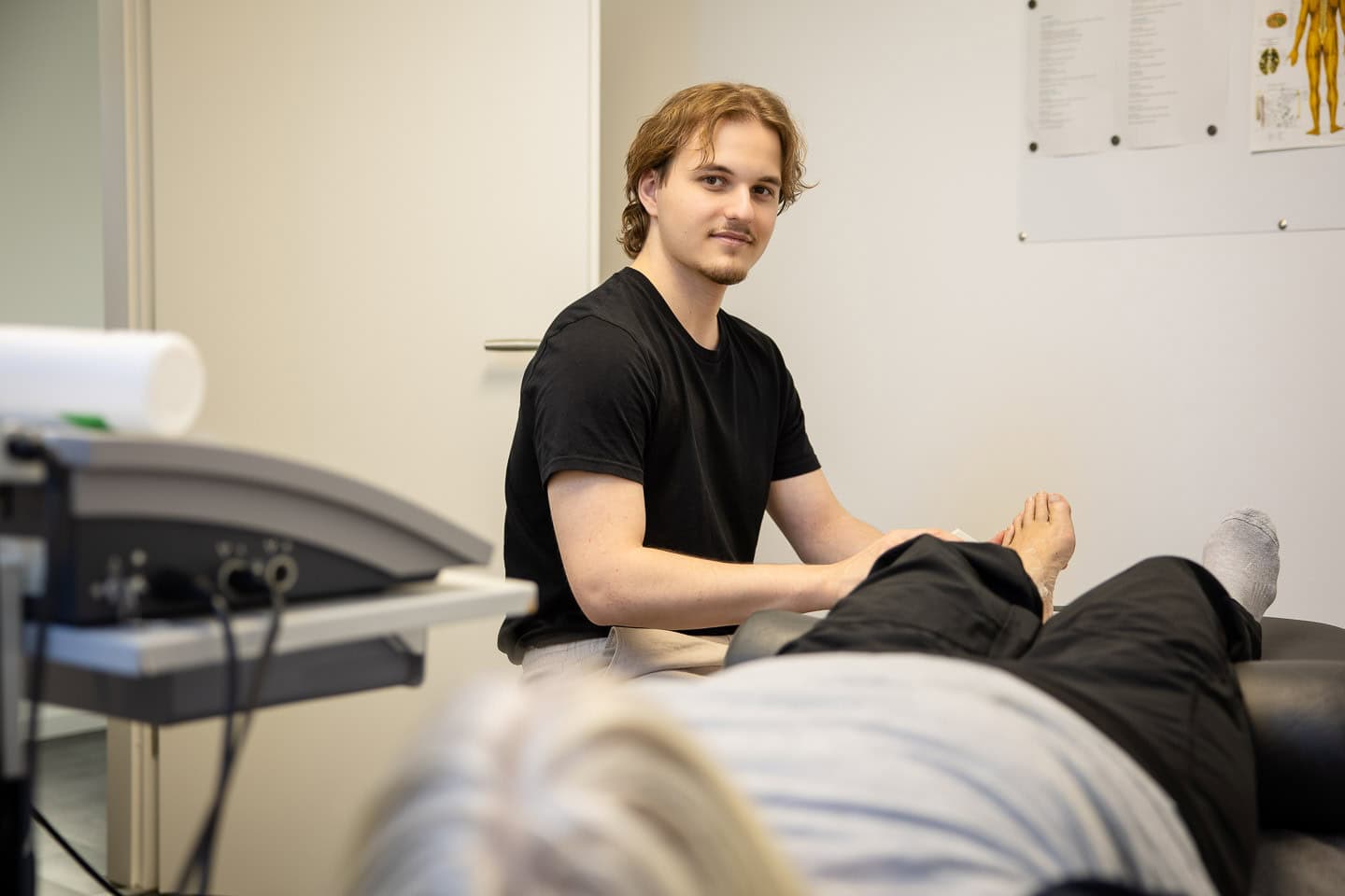 Eine junge Physiotherapeutin führt eine Behandlung bei einem Patienten durch.